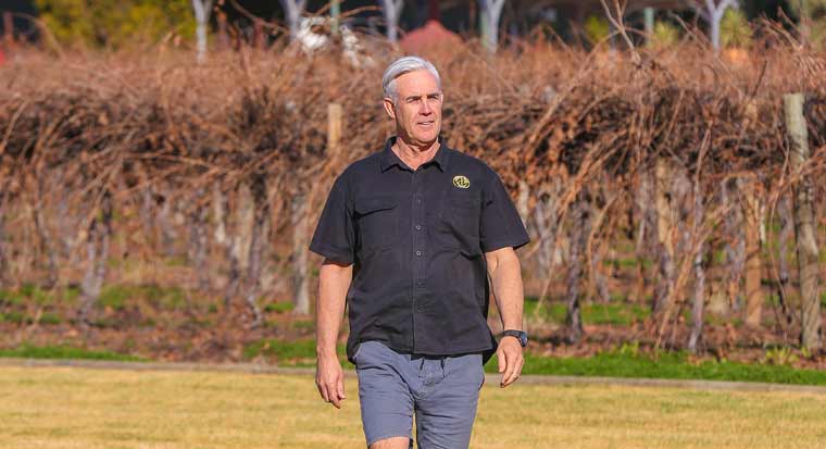 farmer standing in front of grape vines